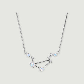 A sterling silver constellation necklace with four pale round moonstones and small clear accents rests on a light gray background.