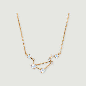 A yellow gold vermeil necklace displays an angular open pendant and fine chain against a soft gray backdrop.