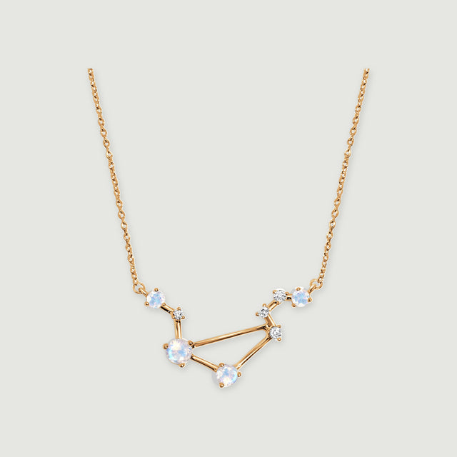 A yellow gold vermeil necklace displays an angular open pendant and fine chain against a soft gray backdrop.