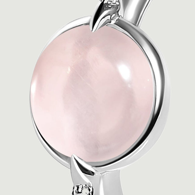 A close view shows the silver setting around the pink cabochon and a pointed prong beside a clear accent.
