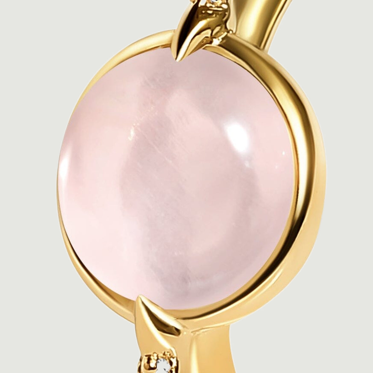 The oval pink stone fills a close view of its polished yellow gold rim and paired pointed prongs.