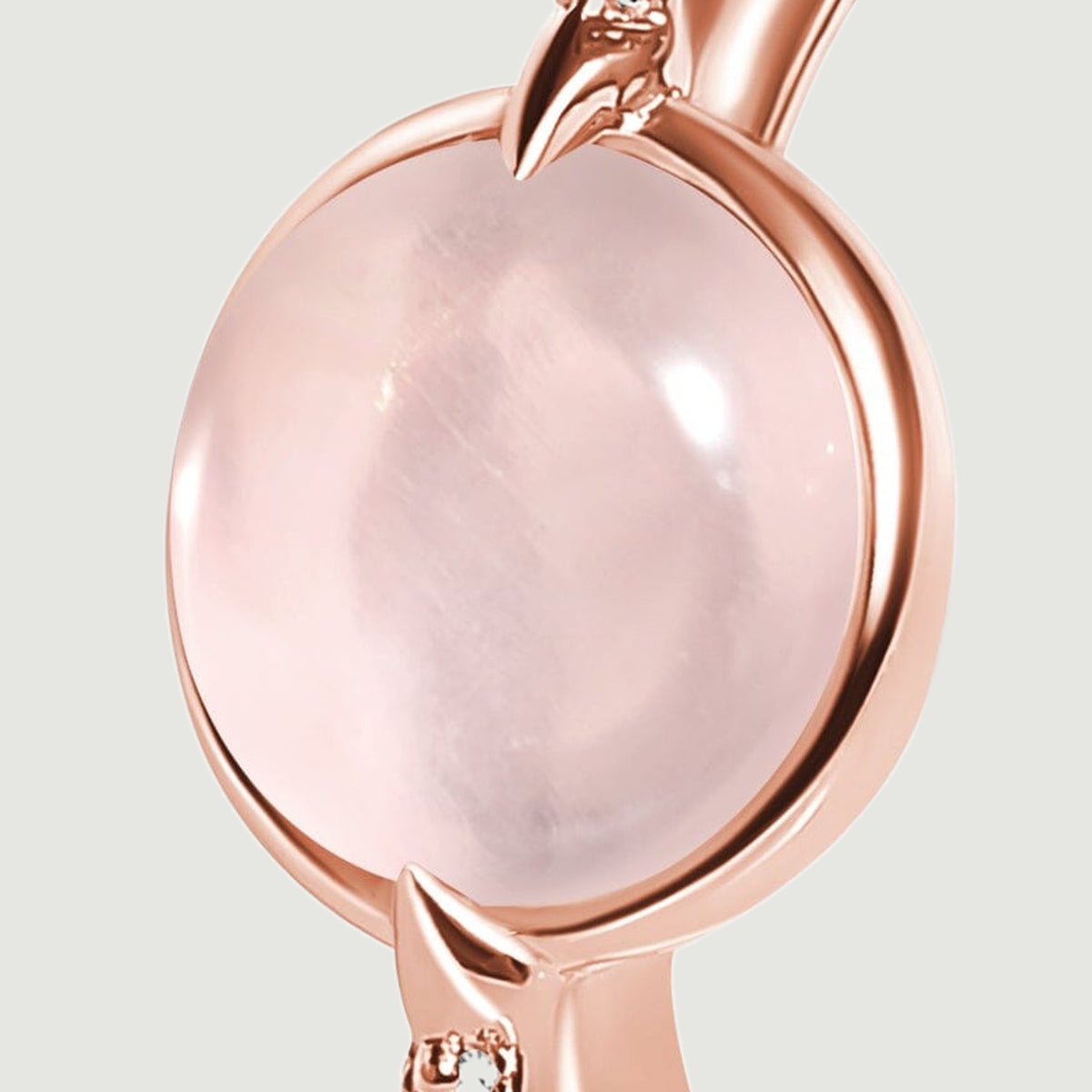 A rose gold setting frames a softly translucent pink cabochon in an angled close-up.