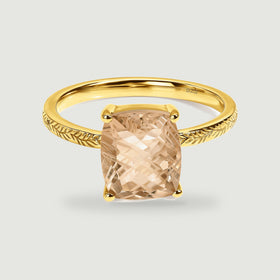 A yellow gold vermeil ring with a champagne-colored rectangular stone sits centered on a pale gray background.