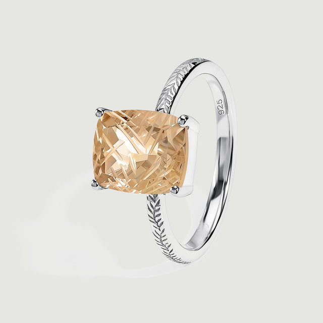 An angled silver ring shows its raised four-prong setting, carved rectangular quartz and engraved shoulders.