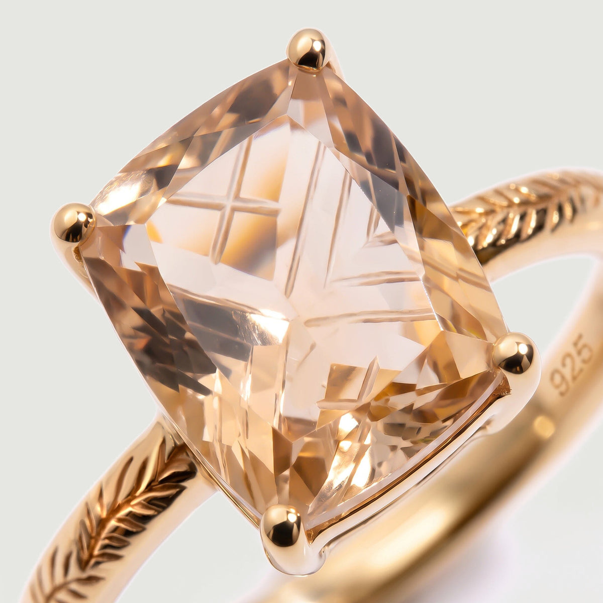 A close view reveals the intersecting cuts of champagne quartz, rounded gold prongs and leaf engraving.