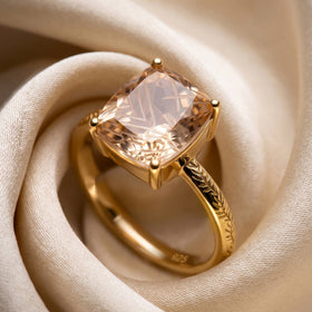 A champagne quartz ring with a leaf-patterned yellow gold vermeil band lies among folds of ivory cloth.