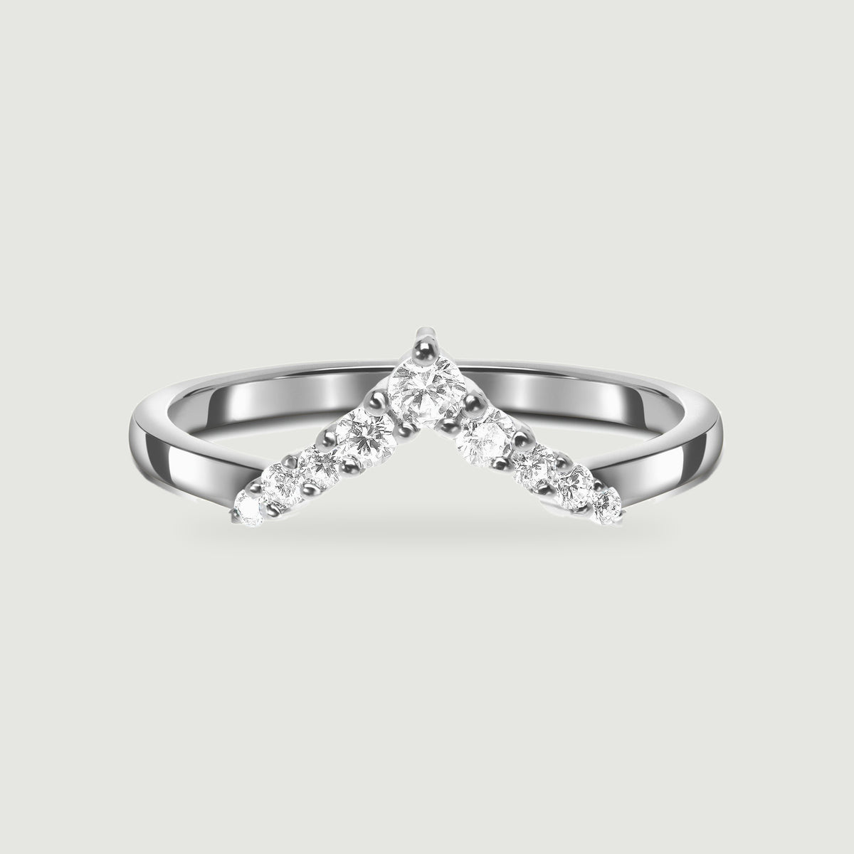 A polished silver chevron ring with round clear stones is centered on a pale gray background.