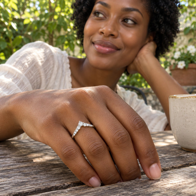 A woman wears a silver chevron ring while resting her hand on a wooden garden table.