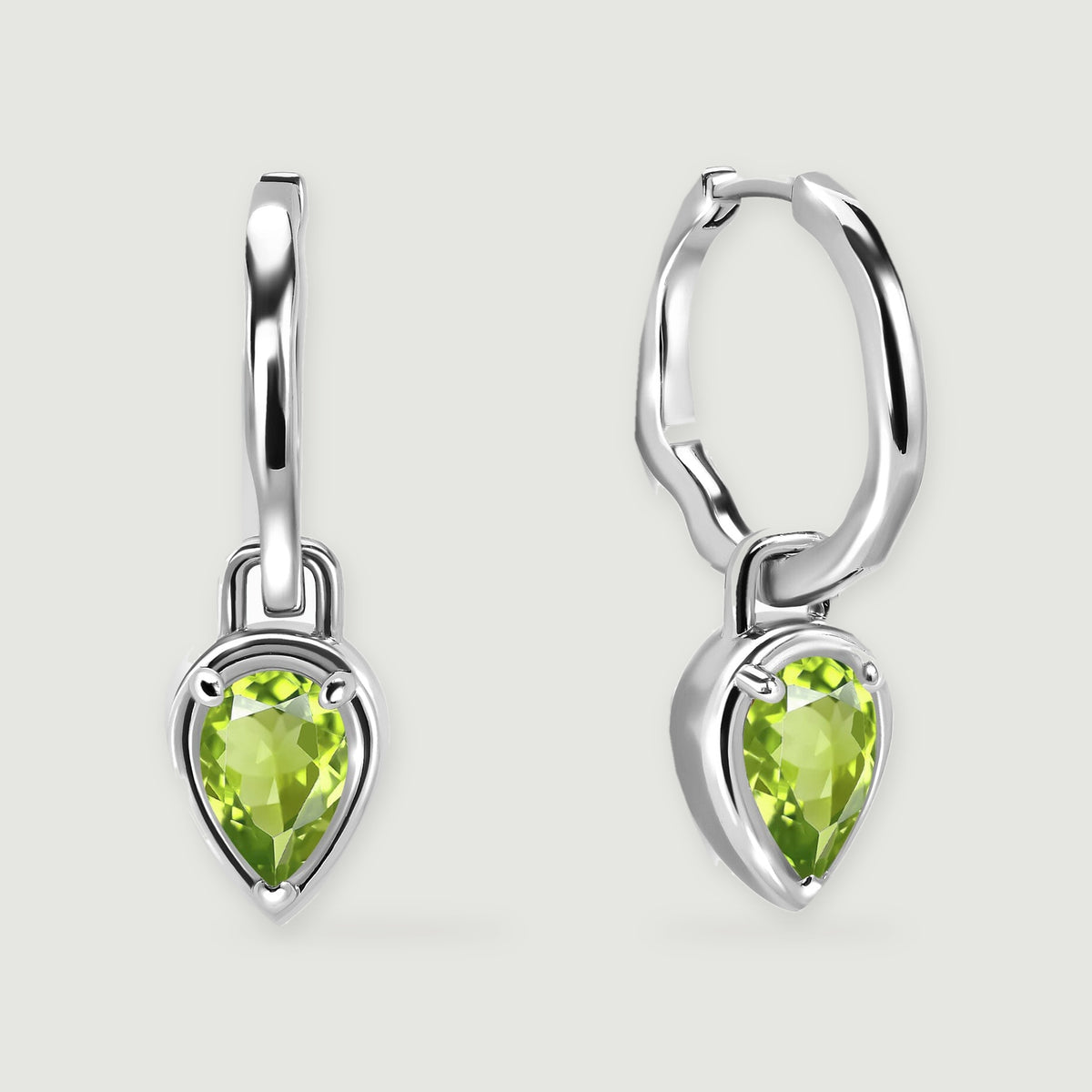 Two silver-tone hoop earrings with pear-shaped green peridot drops are centered on a light gray background.