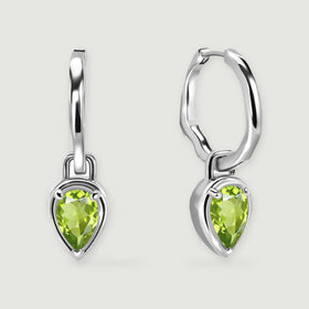 Two silver-tone hoop earrings with pear-shaped green peridot drops are centered on a light gray background.