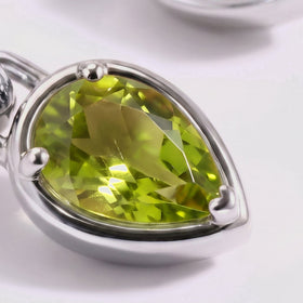 A close view shows the facets and three rounded prongs around a green pear-shaped stone in a silver-tone setting.