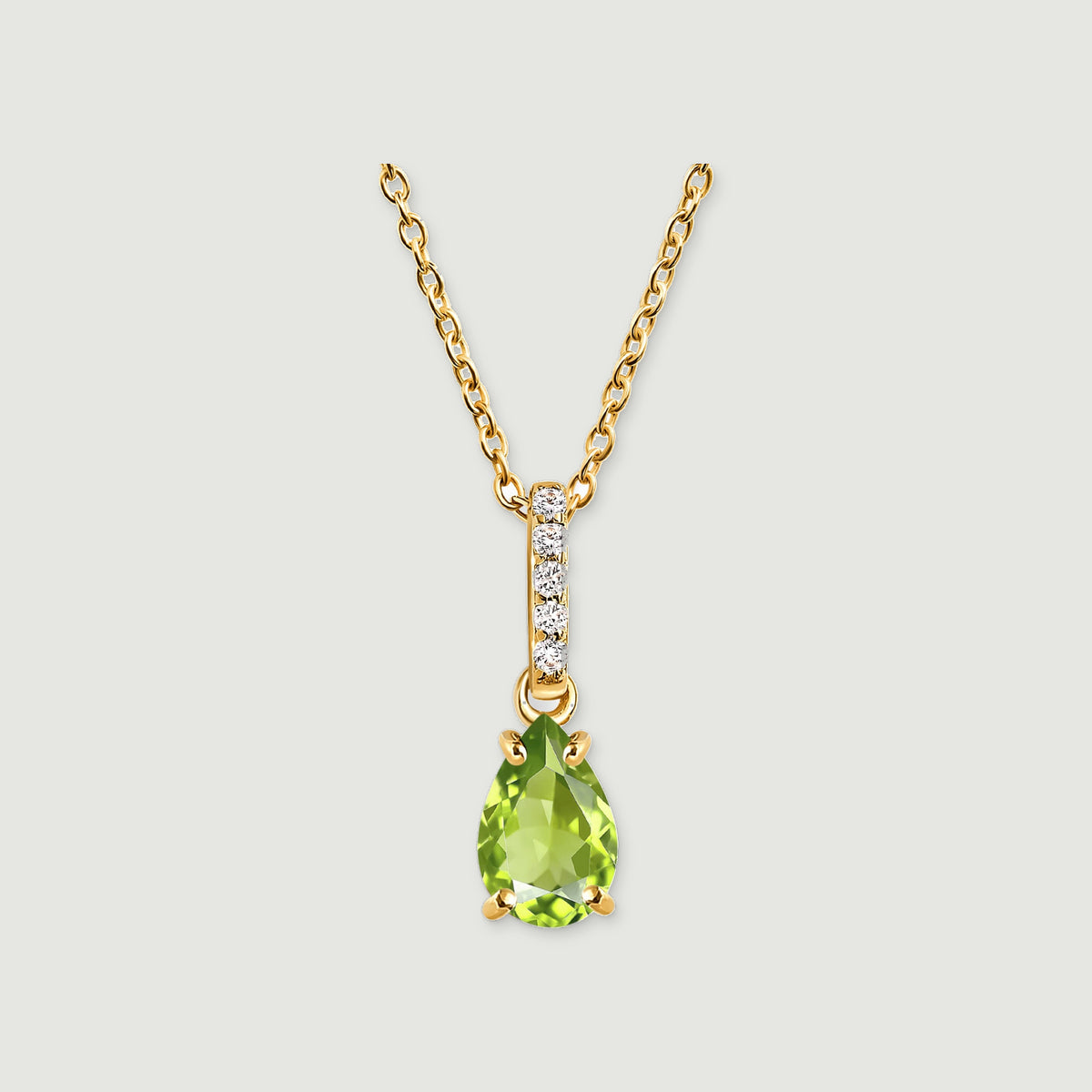 A pear-shaped green peridot hangs beneath five round white stones on a yellow gold chain against a light gray background.