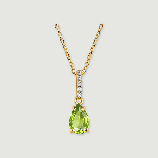 A pear-shaped green peridot hangs beneath five round white stones on a yellow gold chain against a light gray background.