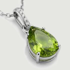 The silver pendant is shown at an angle with an open side setting, rounded prongs, and a row of white stones.