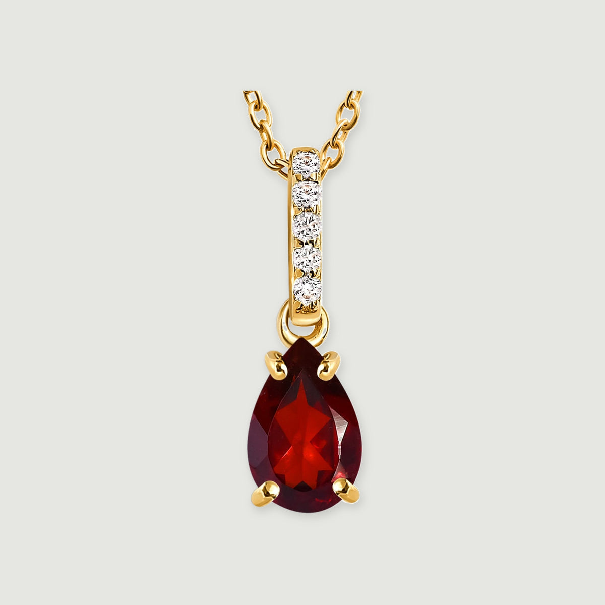 A pear-shaped red garnet pendant hangs below a yellow gold vermeil bail with five clear accents on a light gray background.