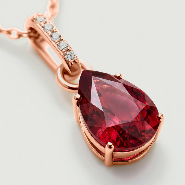 A close view reveals the rose gold setting around the garnet and the row of five clear accents above it.