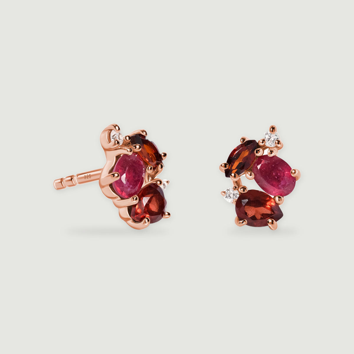 Rose gold vermeil earrings stand side by side with faceted red stones and a visible stud post against a soft gray background.
