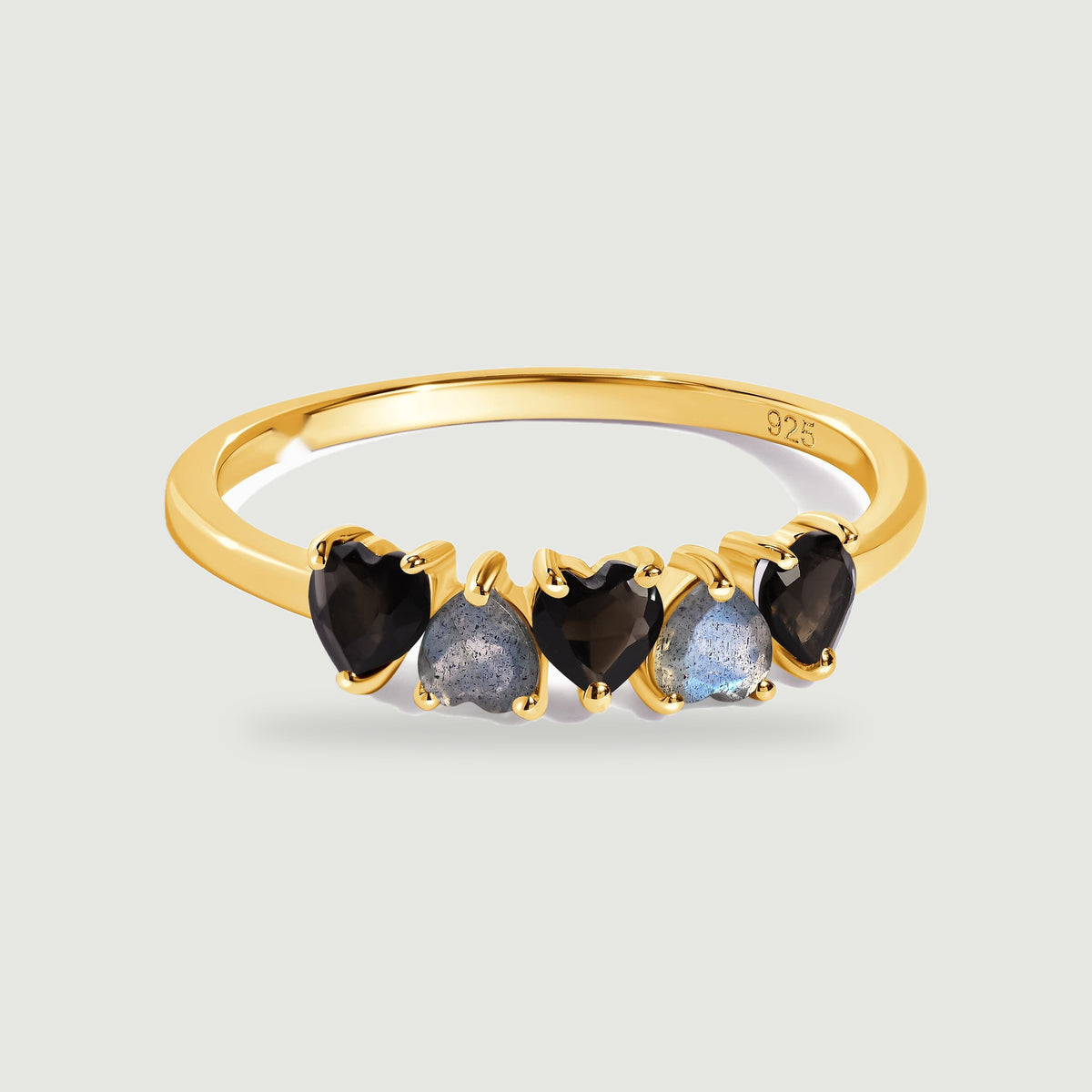 A yellow gold vermeil band holds a row of black obsidian and blue-gray labradorite hearts above a soft contact shadow.