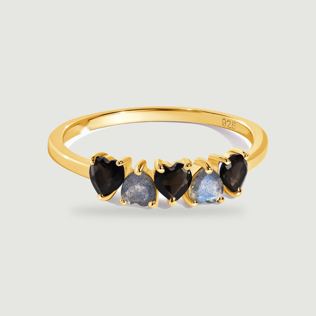 A yellow gold vermeil band holds a row of black obsidian and blue-gray labradorite hearts above a soft contact shadow.