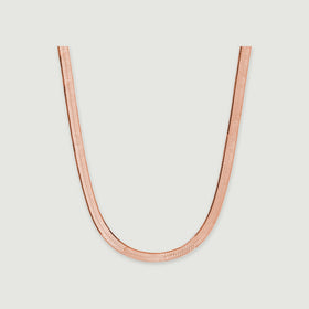 A rose gold herringbone chain displays closely fitted links against a pale gray background.