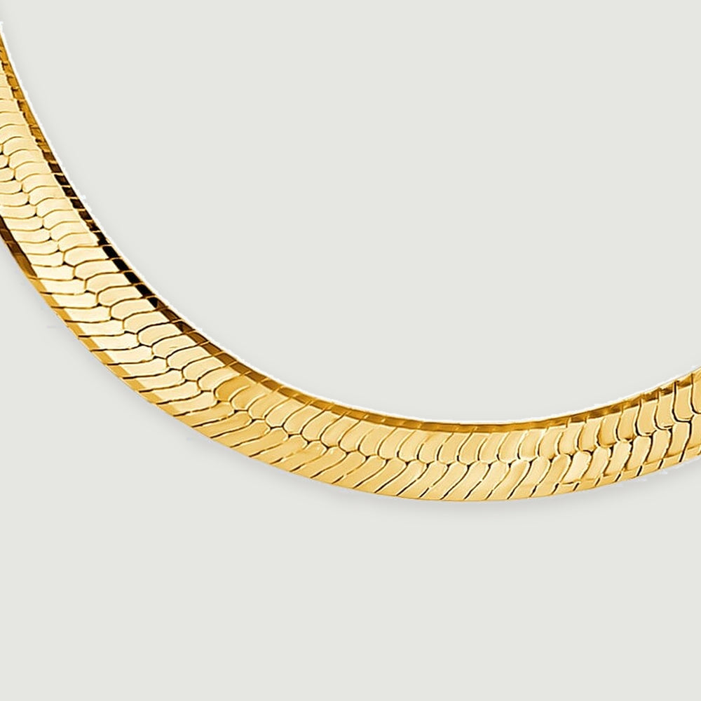 A close view of the yellow gold necklace shows diagonal herringbone links along its lower curve.