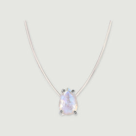 A pear-shaped moonstone in silver prongs hangs from a fine clear cord against a pale gray background.
