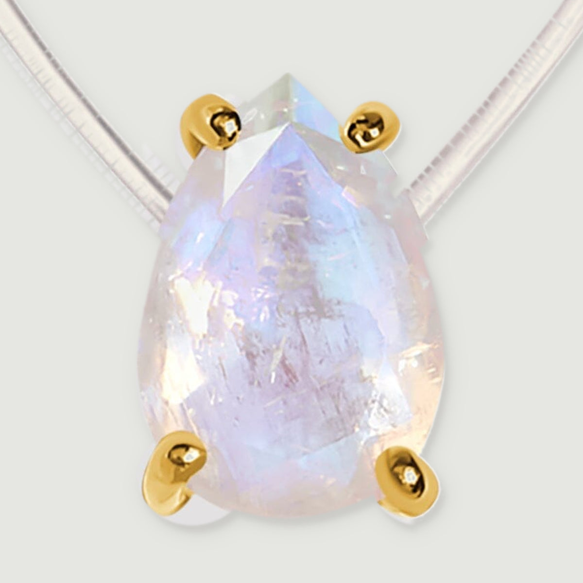 Four yellow gold prongs hold a translucent moonstone with pale blue and peach reflections.