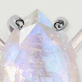 A tight detail reveals the pointed moonstone tip, upper silver prongs, and intersecting translucent facets.