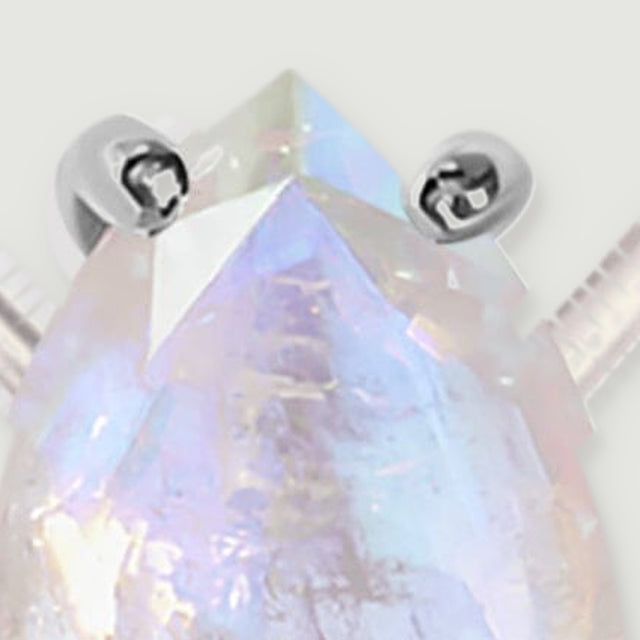 A tight detail reveals the pointed moonstone tip, upper silver prongs, and intersecting translucent facets.