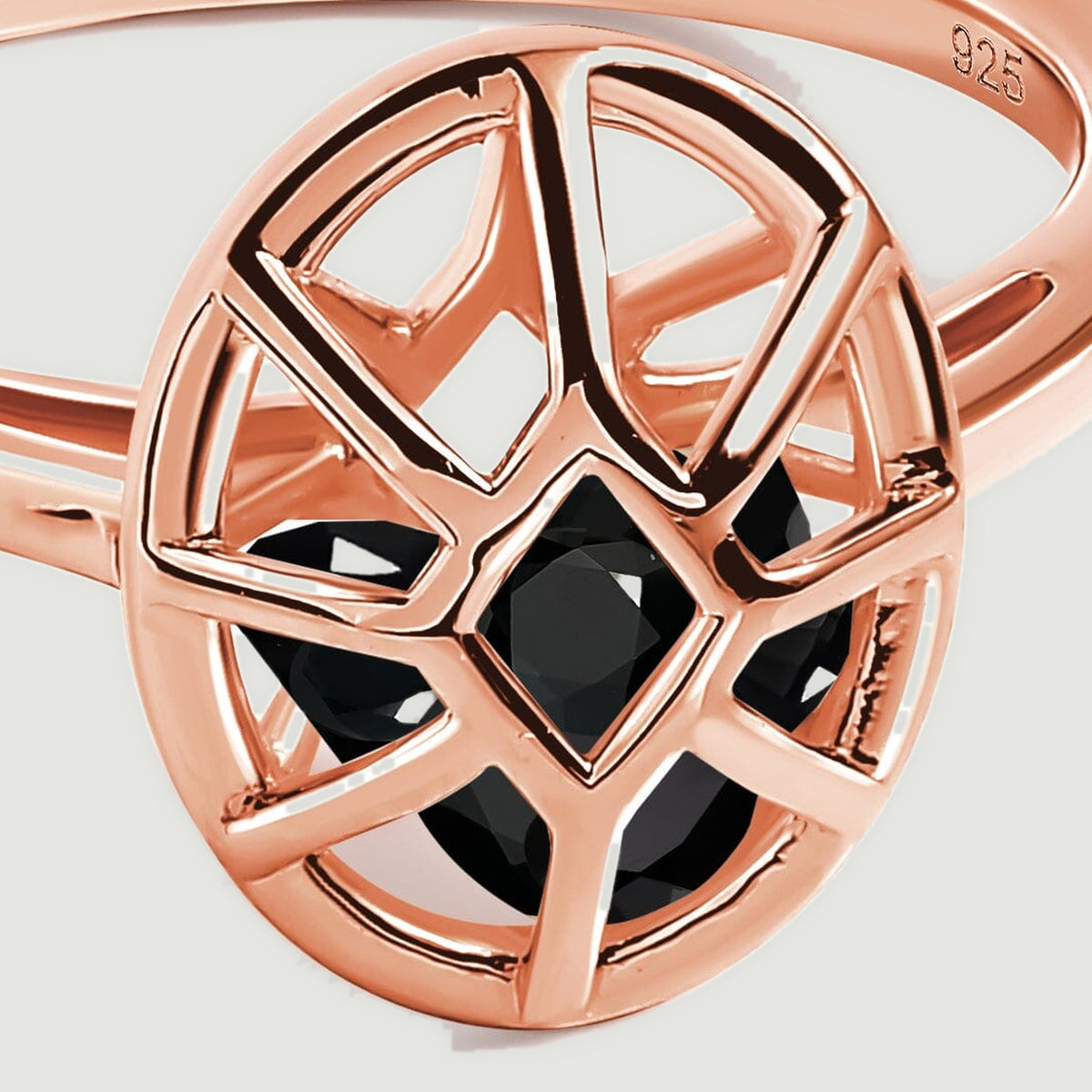 A close view shows black faceted stones beneath the geometric rose gold bars of the oval setting.