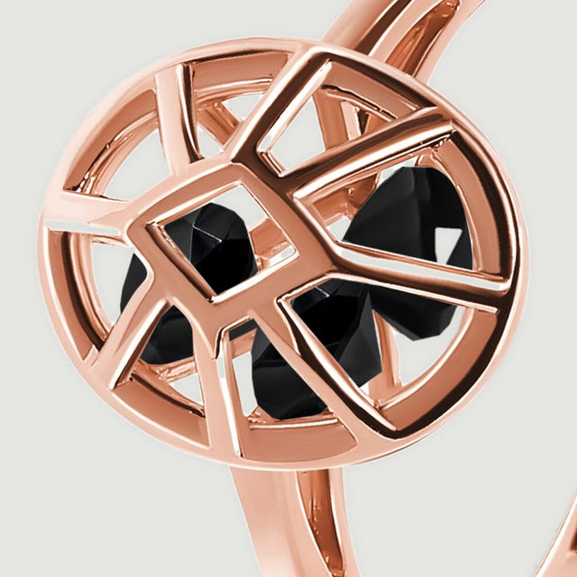 The angled oval setting reveals polished rose gold edges and black stones inside the open cage.