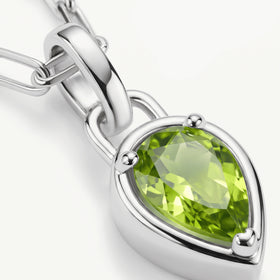 A close view shows the green gemstone facets, rounded silver-tone prongs, and polished pendant bail.