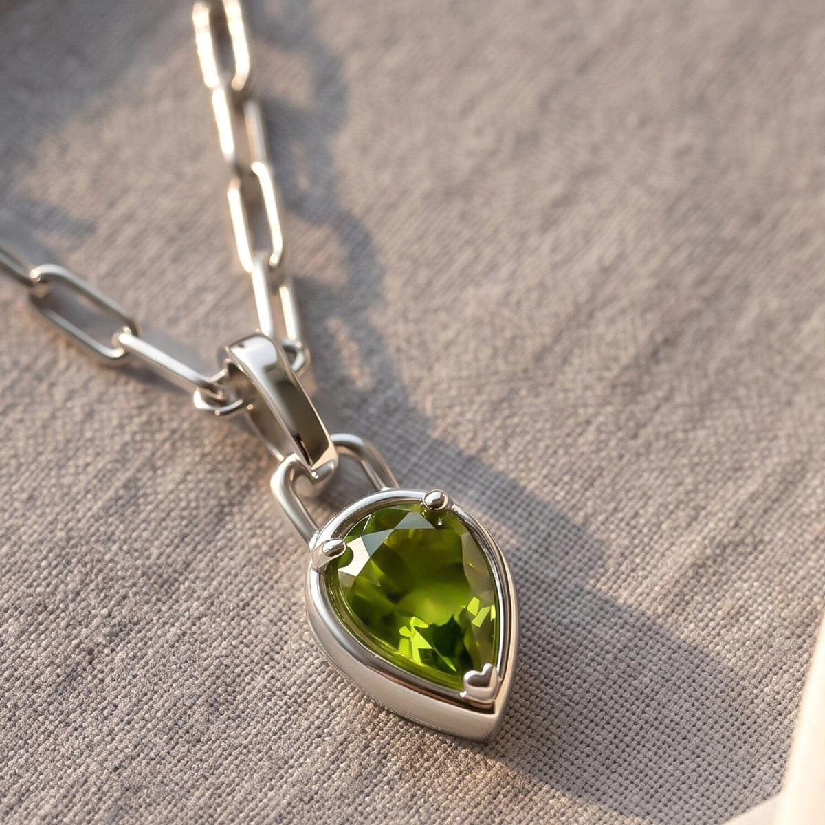 An angled detail reveals the raised silver-tone rim and prongs around the green peridot pendant.