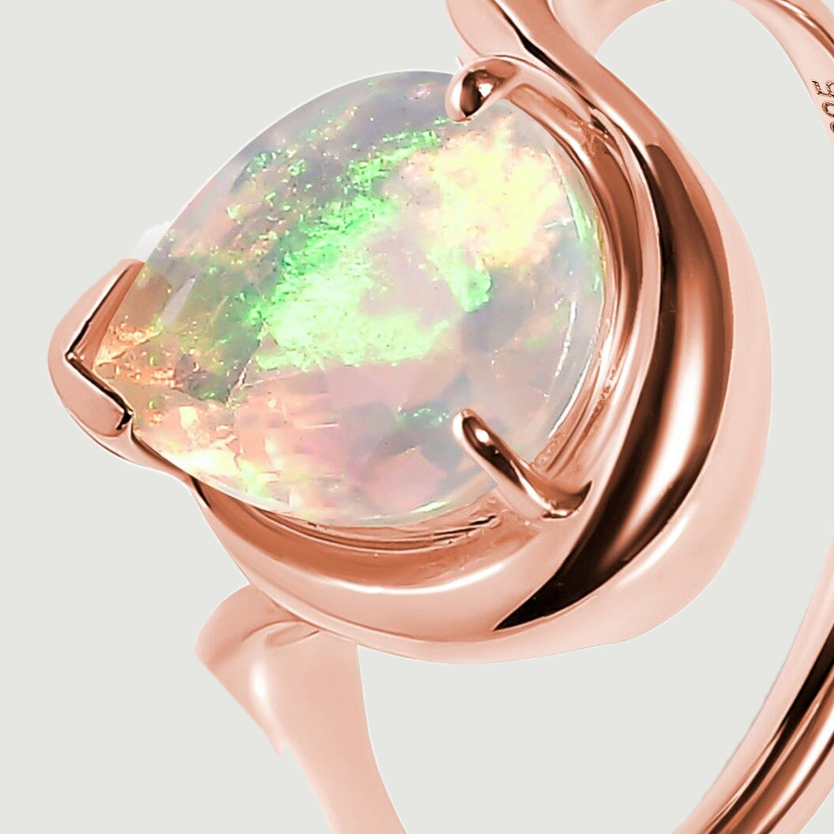 The raised opal setting and curved rose gold shoulder are shown from an oblique angle.