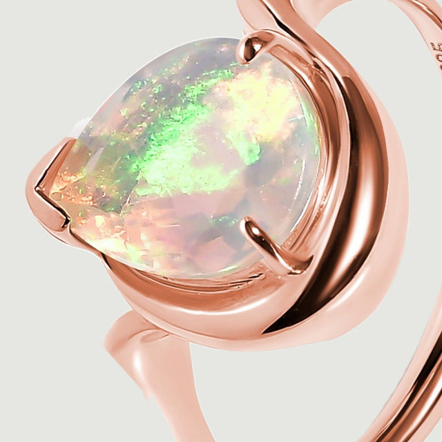 The raised opal setting and curved rose gold shoulder are shown from an oblique angle.