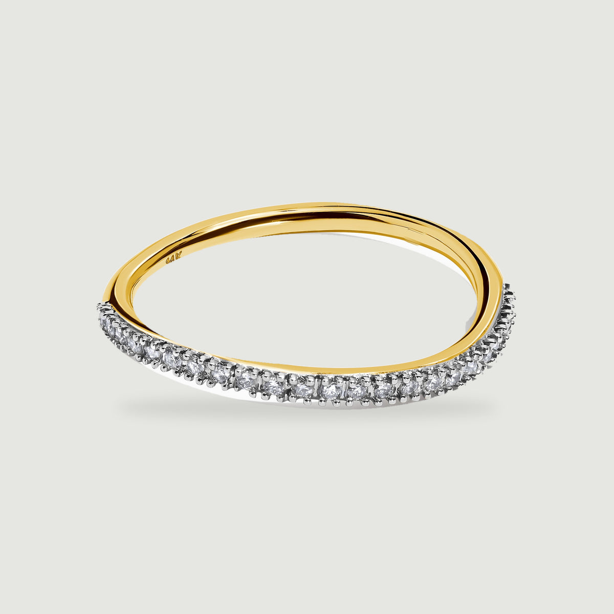 A yellow gold band curves behind a bright row of round diamonds on a light gray surface.