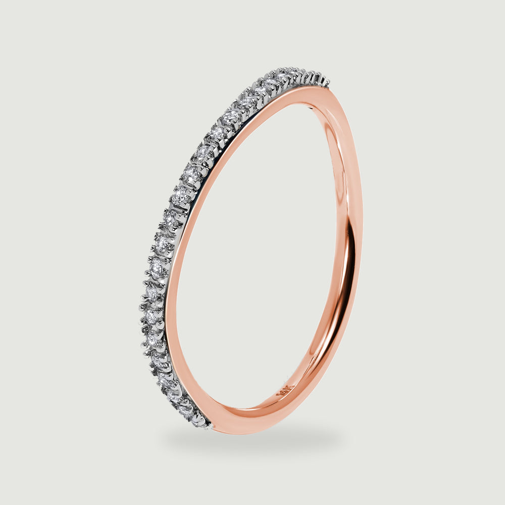 A rose gold ring stands upright at an angle, revealing the raised diamond settings and slim inner band.