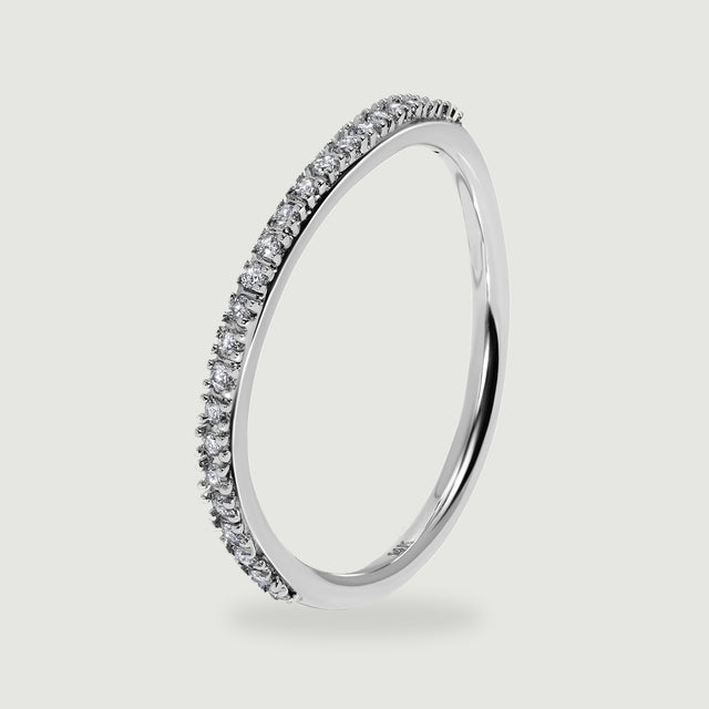 An upright white gold ring shows the side of its round diamond settings above a soft shadow.
