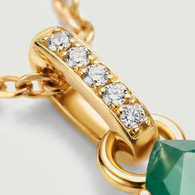 Five round clear stones sit along a polished yellow gold bail beside oval chain links.