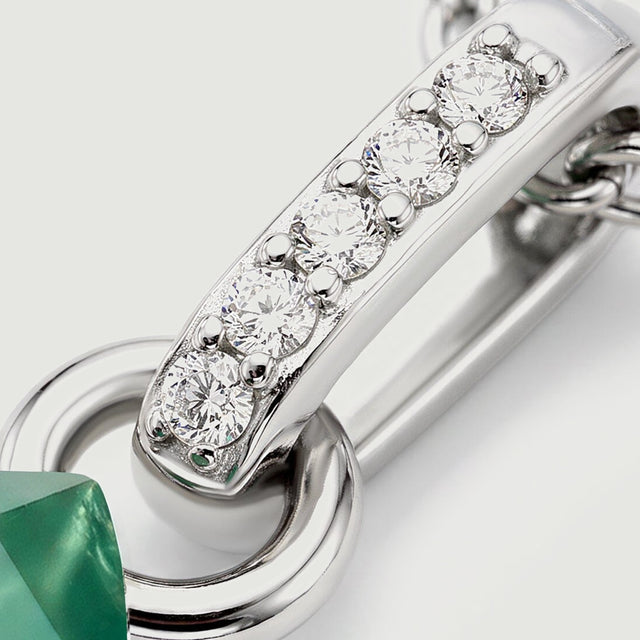 A diagonal silver bail carries five round clear stones above a polished connecting ring.