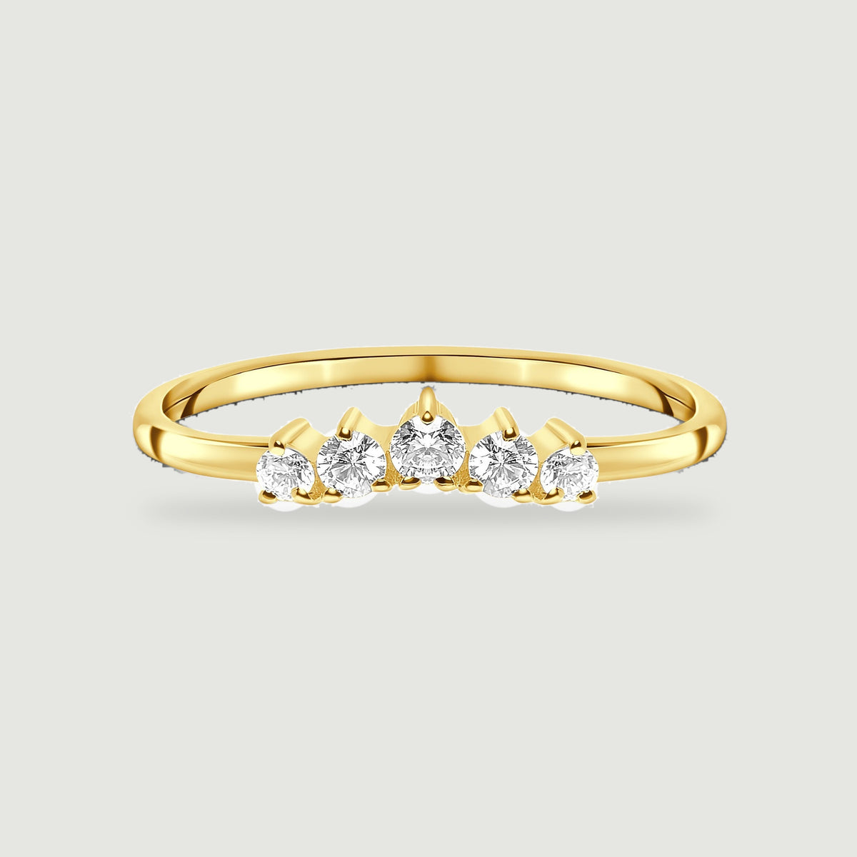 Five graduated white zircon stones line the front of a yellow gold vermeil ring on a pale gray surface.