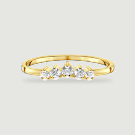 Five graduated white zircon stones line the front of a yellow gold vermeil ring on a pale gray surface.