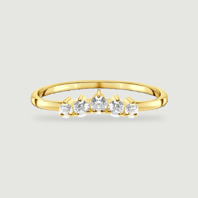 Five graduated white zircon stones line the front of a yellow gold vermeil ring on a pale gray surface.
