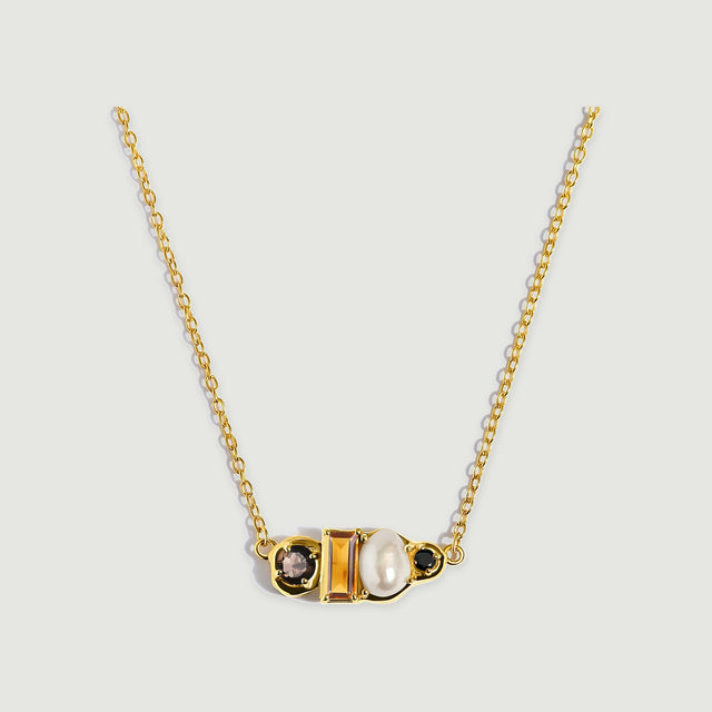 A yellow gold vermeil necklace presents a horizontal cluster of faceted amber citrine, a cream pearl and round dark gemstones.