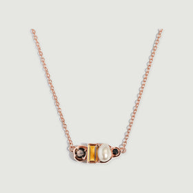 A rose gold vermeil necklace displays a polished four-stone setting with a rectangular citrine beside a lustrous oval pearl.