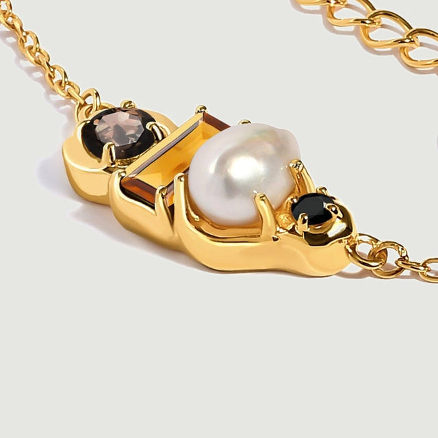 A side view reveals the yellow gold vermeil prongs around the irregular pearl, rectangular citrine and dark round stones.