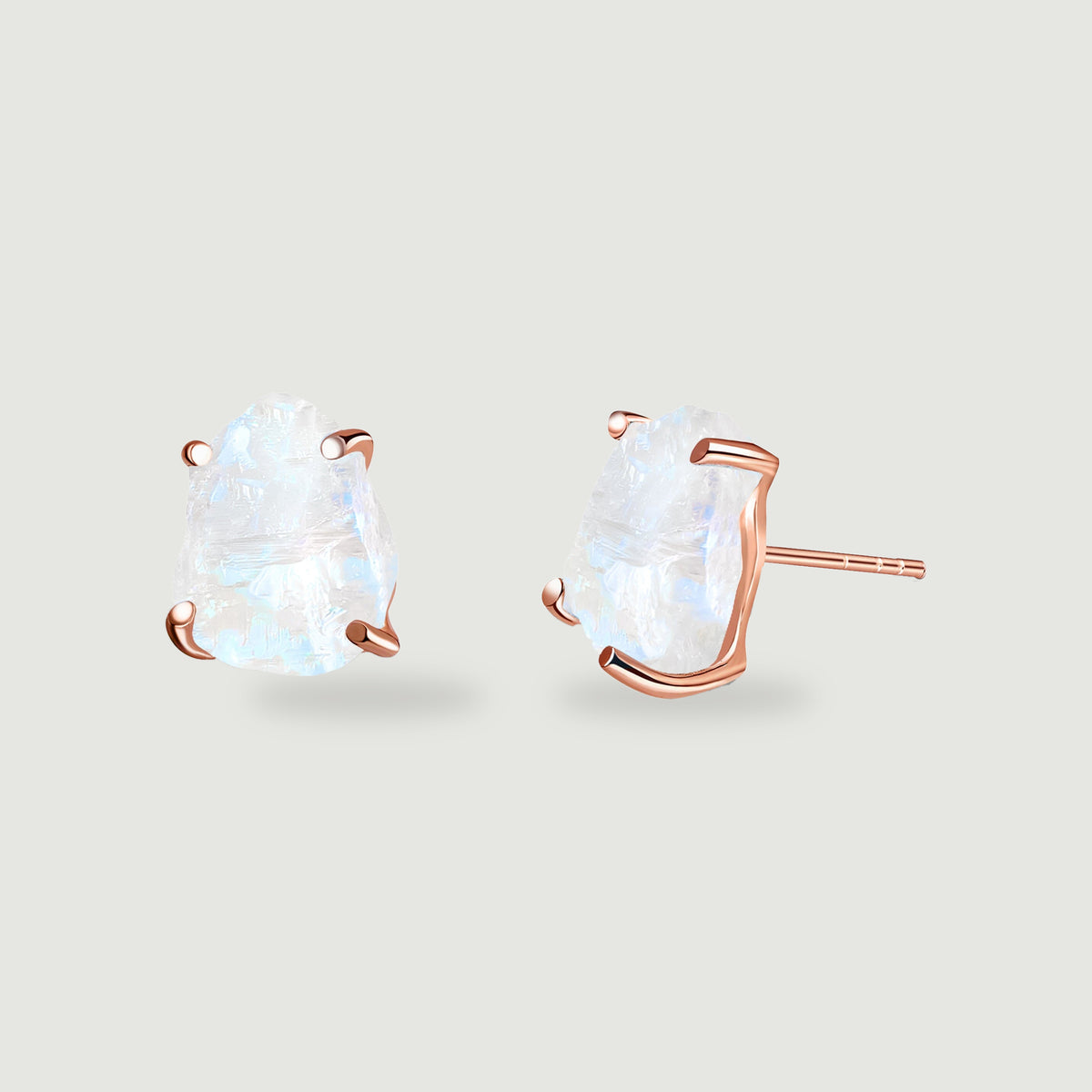 Two pale moonstone studs are held by rose gold prongs, with the side setting facing forward.
