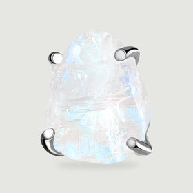 A close view of one raw moonstone stud shows blue flashes and four polished silver prongs.
