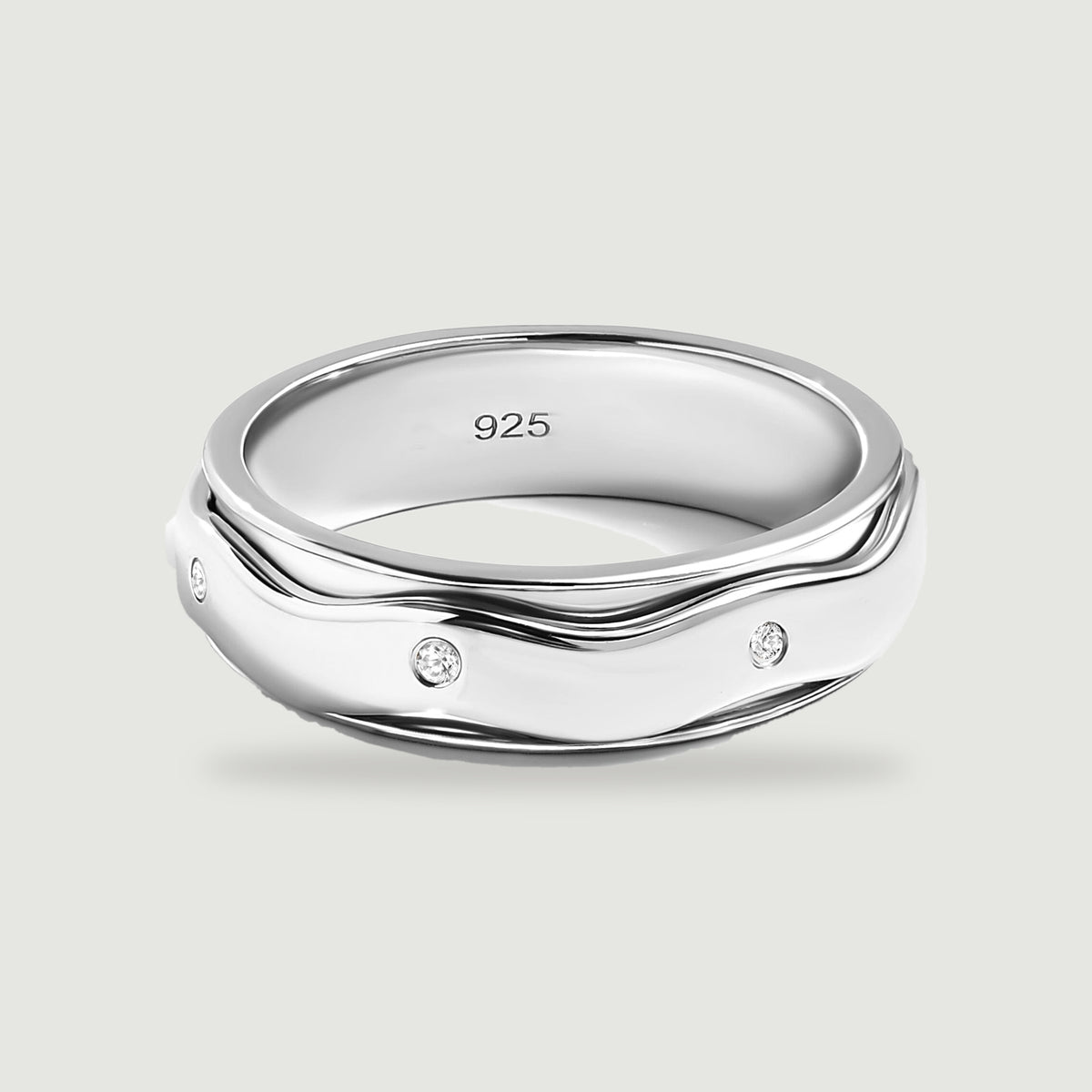 A sterling silver ring with wavy polished edges and three visible round white stones rests on a light gray surface.