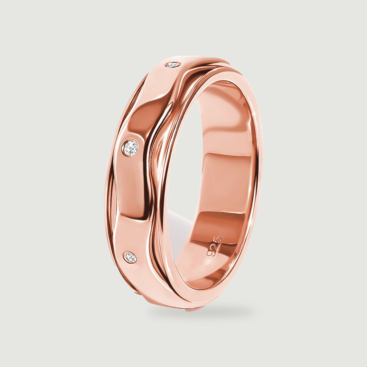 A side view of the rose gold vermeil ring shows its reflective inner band and white stones along the wavy outer surface.